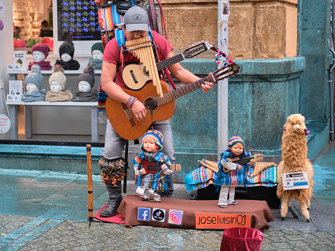 Bilbao, Spain; November 25, 2023: A street musician entertains pedestrians on the streets of Bilbao by accompanying his music with a puppet performance