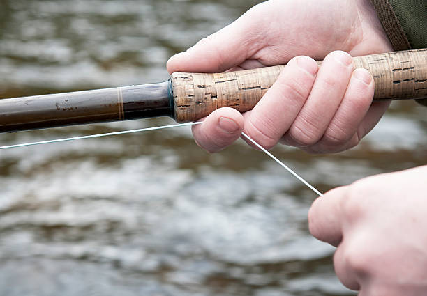 Fly Fishing Close-Up Fly fishing close-up during hand-lining before a cast, with the river water in the background. fly fishing scotland stock pictures, royalty-free photos & images