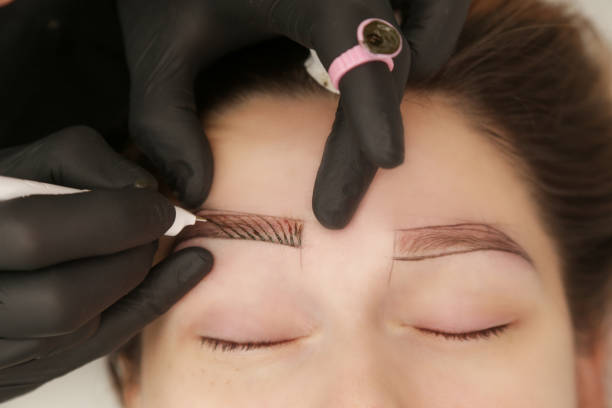 istock Microblading - semi-permanent tattooing technique used for the eyebrows by creating an illusion of a more defined and fuller brow. Artist makes tiny hair-like strokes to create a natural looking brows 1828964208