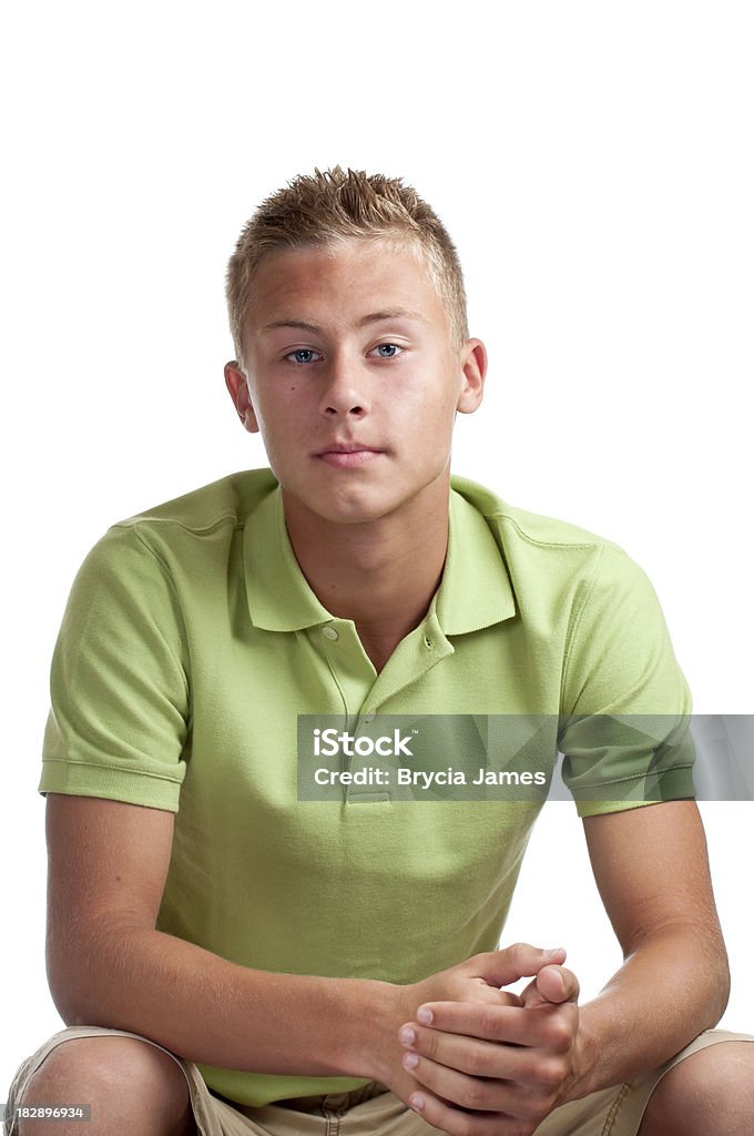 Serious Male Teen Seated "Handsome 14 year-old boy looking into the camera but not smiling, while seated against a white background." 14-15 Years Stock Photo