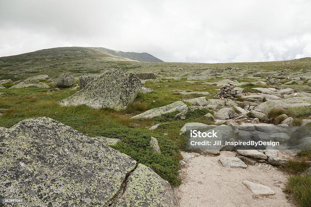 View of Baxter Peak from the Hunt Trail "View from the Hunt trail on top of Mount Katahdin, Maine. The elevation is about 5,000 feet above sea level. The flat area is called the tableland. The Hunt trail is the last part of the northern end of the Appalachian trail. Low cloud cover is seen on the edge of the mountain. Rock piles called cairns mark the trail. Fragile alpine tundra plants can be seen on either side of the trail. Erosion from excessive foot travel widened the trails." Appalachia Stock Photo