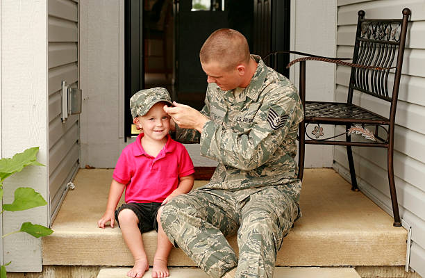 A military styled father letting his son try on his hat Military dad spending time with his son. Placing hat on his head. air force stock pictures, royalty-free photos & images