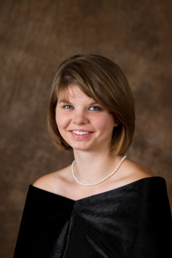 Seen here is a 19 year old young lady sitting for her High School Senior portrait wearing a traditional simple black drape and pearls. Head straight.See other related images here: