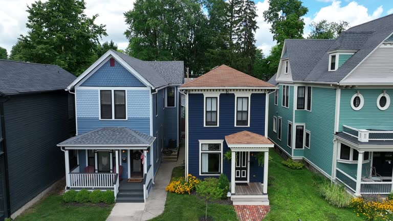 Colorful Victorian homes line a serene suburban street. Aerial push in shot.