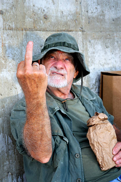Crazy Old Vet Looking Up and Flipping the Bird A Vietnam war veteran (actual) appears to be down and out. In this shot he is gesturing his thoughts on the matter. Scene staged. old man middle finger stock pictures, royalty-free photos & images