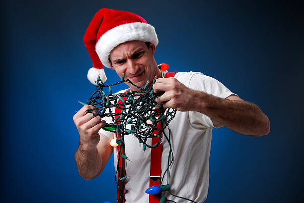 Christmas Light Frustration Man in santa hat frustrated with tangled Christmas lights.Please see other pictures from my portfolio: cebolla stock pictures, royalty-free photos & images