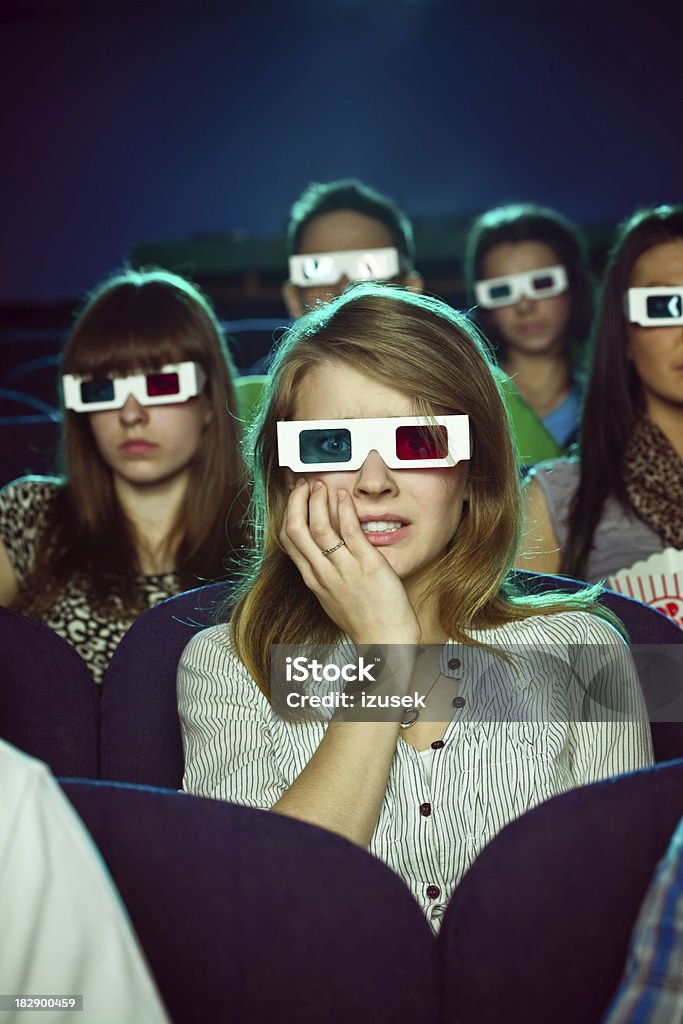 Young people in 3D move theater "Group of young adult people wearing 3D glasses, sitting in the cinema  and watching scary 3D move. Teenage girl sitting in the middle looks frightened." 3-D Glasses Stock Photo