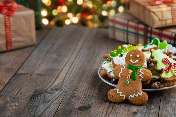 istock Gingerbread man cookie and plate with gingerbread cookies decorated with icing on wooden table. 1829010093