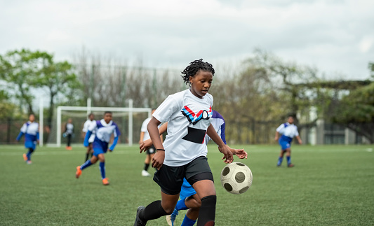 Young female soccer team playing a match together on a sports field outdoors