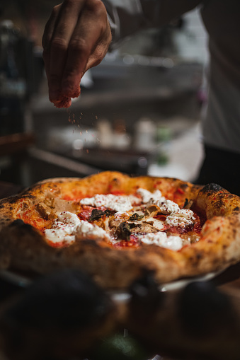 Cook finishing of preparing a delicious pizza in italian restaurant