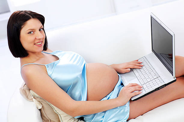 istock Pregnant woman resting on a sofa, using laptop 182901627