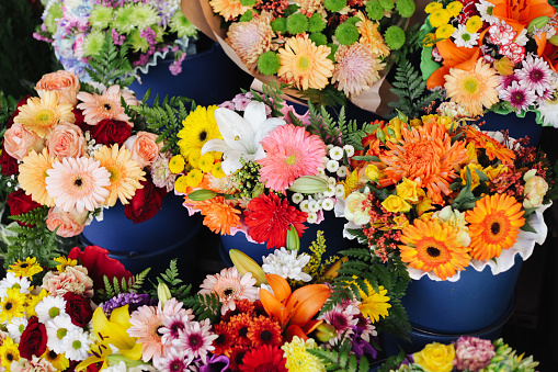 Wide variety of multi colored bouquets displayed in buckets at open-air market stall.