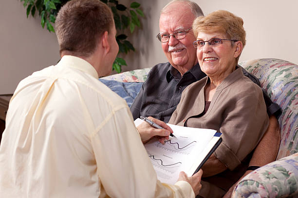 istock Senior couple speaking with a man holding a book with charts 182902670
