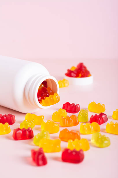 istock Chewable vitamin supplements spilled from a bottle on a pink background vertical view 1829029580