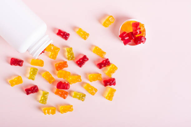 istock Chewable vitamin supplements spilled from a bottle on a pink background top view 1829030121