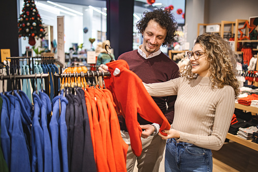 Young couple in the clothing store looking at clothes