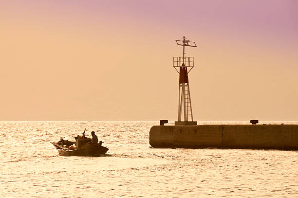 Greek fishing boat leaves Sami harbour at sunset. Kefalonia