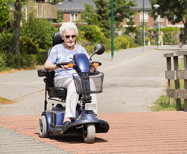 istock Elderly woman driving mobility scooter down quiet street 182904338
