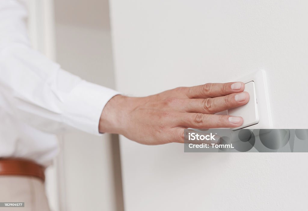 Uma macho mão passando sobre a luz com o interruptor na parede. - Royalty-free Interruptor de Luz Foto de stock