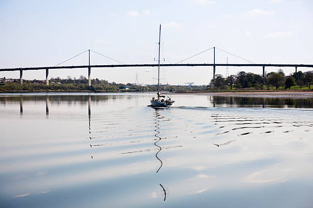 Sailing Below The Erskine Bridge Sailing yacht sailing up the River Clyde with the Erskine Bridge behind and Glasgow beyond. clyde river stock pictures, royalty-free photos & images
