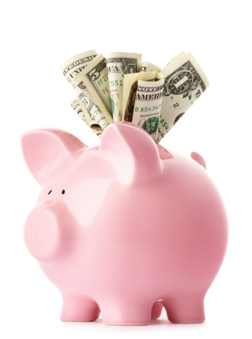 Savings - pink piggy bank with US dollars.