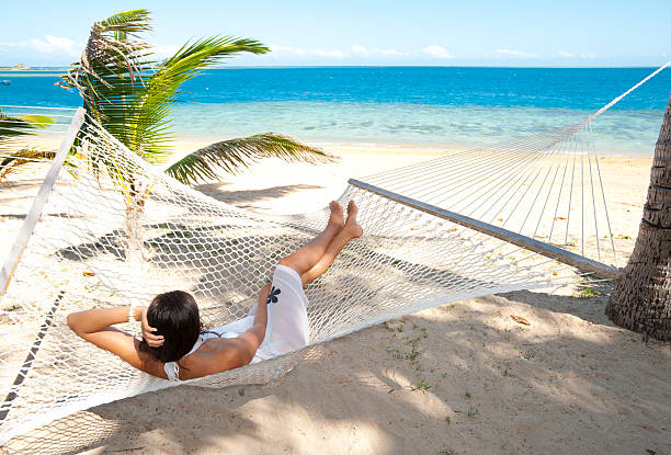 Woman relaxing in a hammock on the beach Woman relaxing in a hammock on the beach with water background fiji stock pictures, royalty-free photos & images