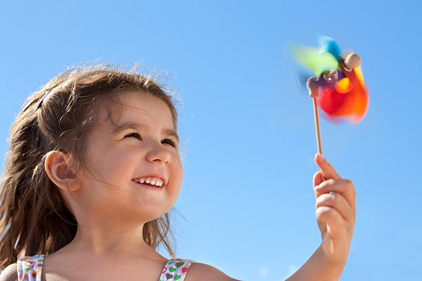 Little smiling girl is holding a pinwheel in front of the clear sky. Conceptual image about environment and happiness.Similar pictures: