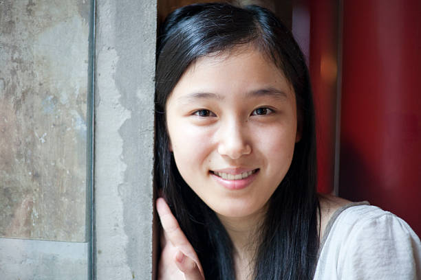 Asian girl inside the window Beautiful asian girl smiling to the camera in a cafe. 21st century style stock pictures, royalty-free photos & images