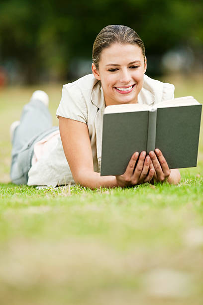 istock Attractive Woman Reading a Book on the Grass 182906571