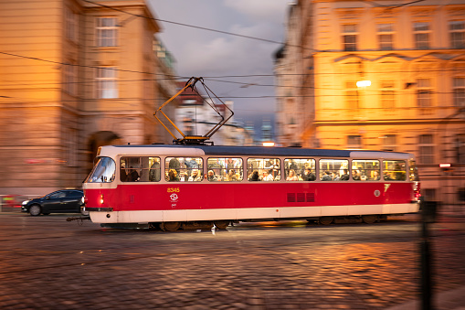 Prague, Czechia - September 17, 2022:  Street car tram public transportation speeds along the cobblestone streets of Old Town at night Czech Republic Czechia