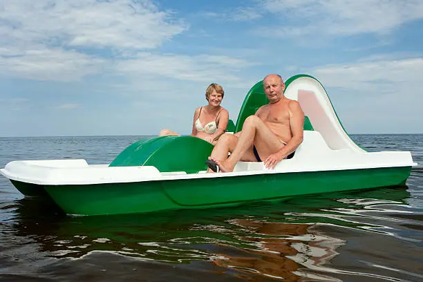 happy senior couple resting on pedal catamaran