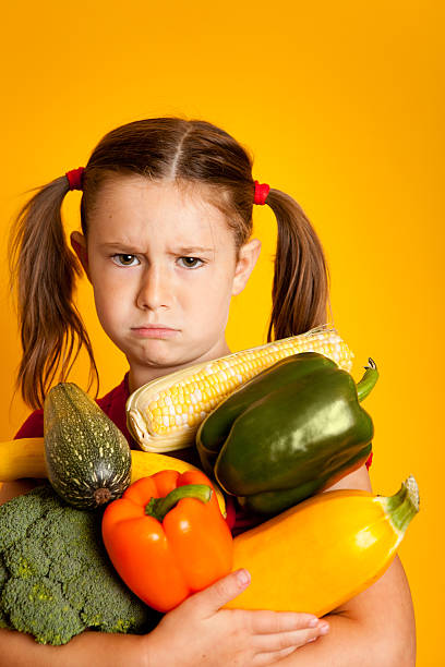 istock Grumpy Young Girl Holding Bell Peppers, Broccoli, Squash, Zucchini 182906977