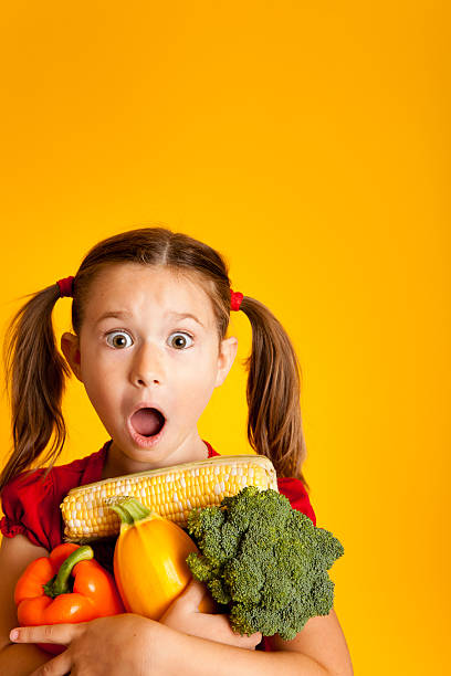 istock Surprised Young Girl Holding Orange Bell Pepper, Broccoli, Squash, Corn 182906985