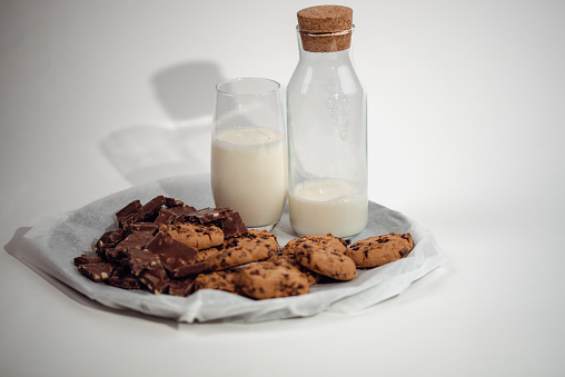 milk bottle with glass of milk and cookies on white background
