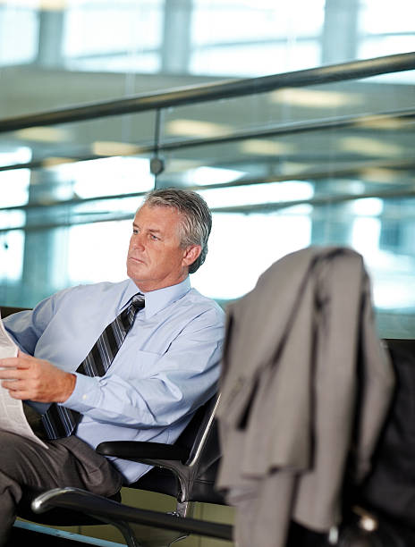 Mature businessman reading a newspaper at airport Confident mature businessman reading a newspaper at airport newspaper airport reading business person stock pictures, royalty-free photos & images