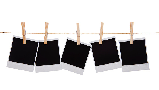 Blank instant photo prints on a washing line. Isolated on white