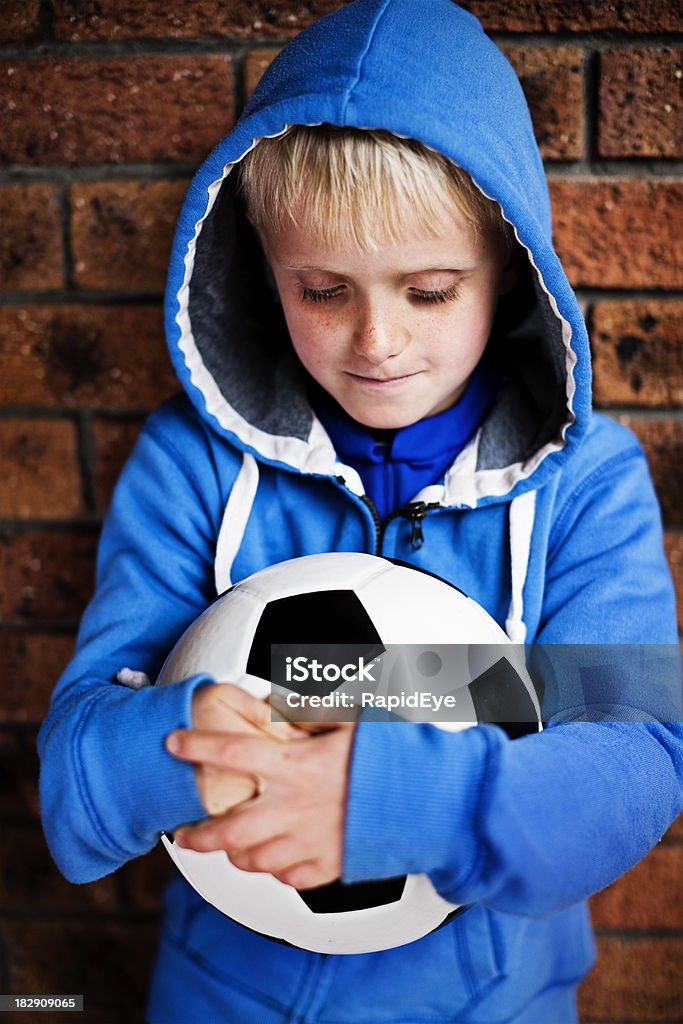 Ragazzo carino capelli biondi si affaccia sul pallone da calcio ha premuto - Foto stock royalty-free di 6-7 anni