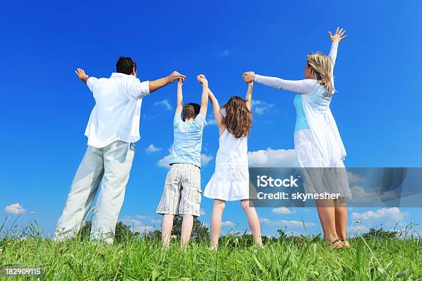 Foto de Vista Traseira Da Família Em Pé Com As Mãos Levantadas Ao Ar Livre e mais fotos de stock de Família