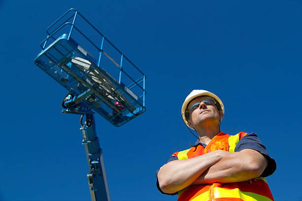 Lift Operator A construction worker stands beneath his equipment. crane machinery photos stock pictures, royalty-free photos & images