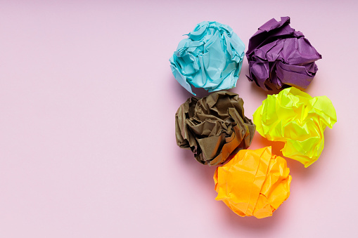 Crumpled Colorful Paper Balls on Pink Background, Uselessness Concept