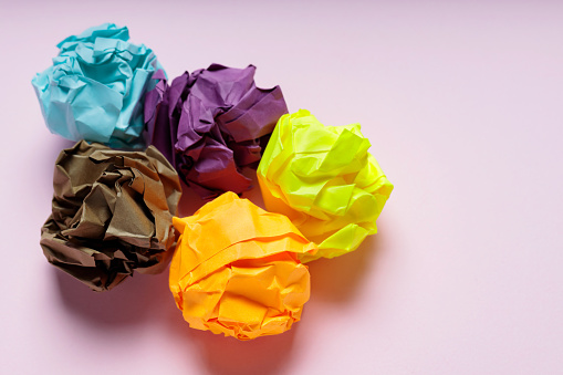 Crumpled Colorful Paper Balls on Pink Background, Uselessness Concept