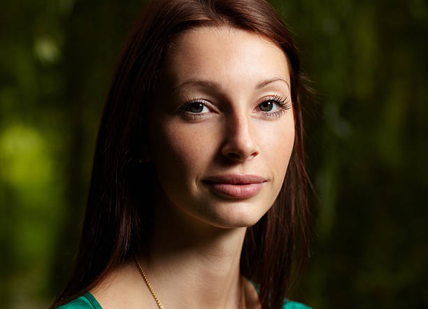 Portrait of a beautiful young woman standing outdoors in a forest.