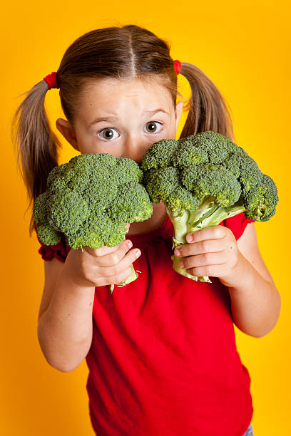 istock Young Girl Peeking from Behind Broccoli 182910998