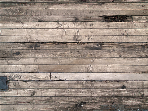 Original, old wooden floor of the sailing boat. Boards are arranged horizontally. Natural scratches and cracks visible.
