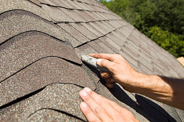 Roofer Trimming a New Shingle on Home Construction Project stock photo