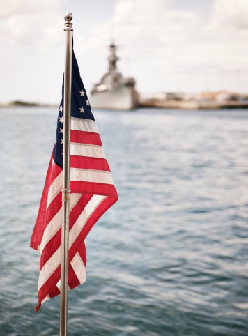 American flag and military ship in Pearl Harbor.