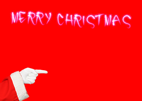 Santa Klaus pointing Merry Christmas written on red background.