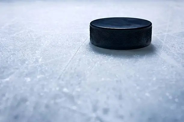 A hockey puck on ice textured by skate marks.Click on an