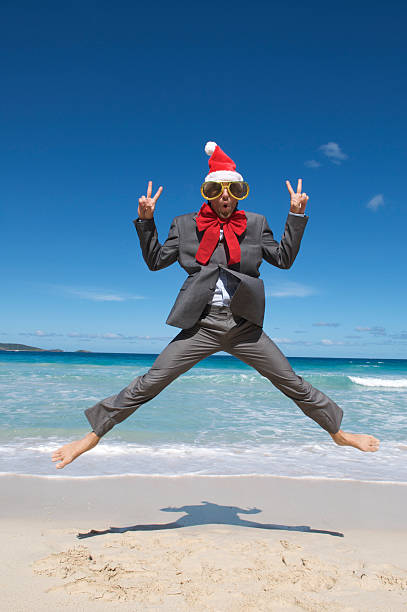istock Santa Hat Businessman Jumps for Joy on Beach 182915341