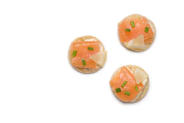 Three smoked salmon and cream cheese canapes isolated on a white background